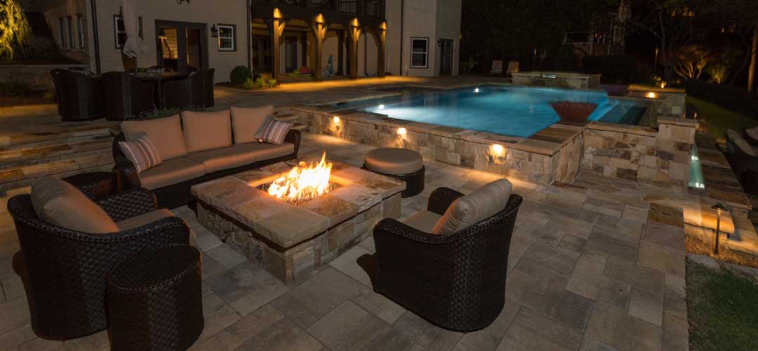 natural stone fire pit table next to pool